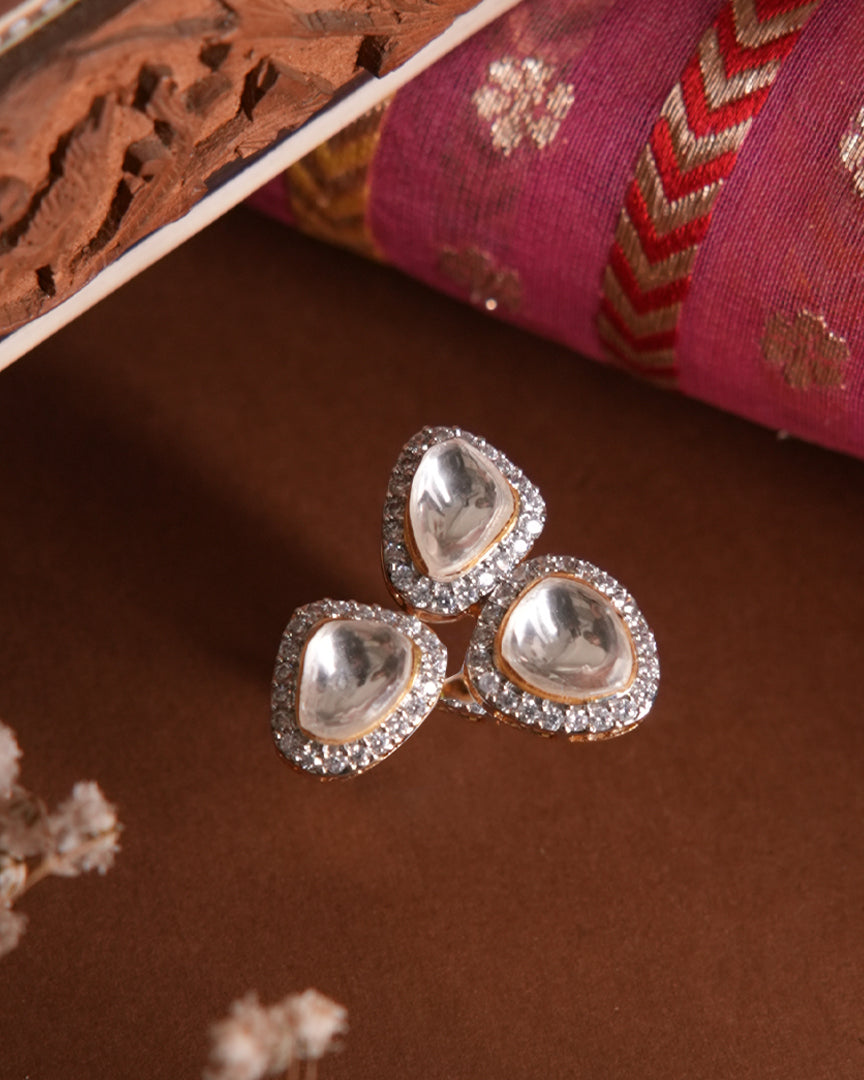 Artistic display of the Mira Ring by Vasundhara, with three gleaming kundan stones bordered by sparkling diamonds.