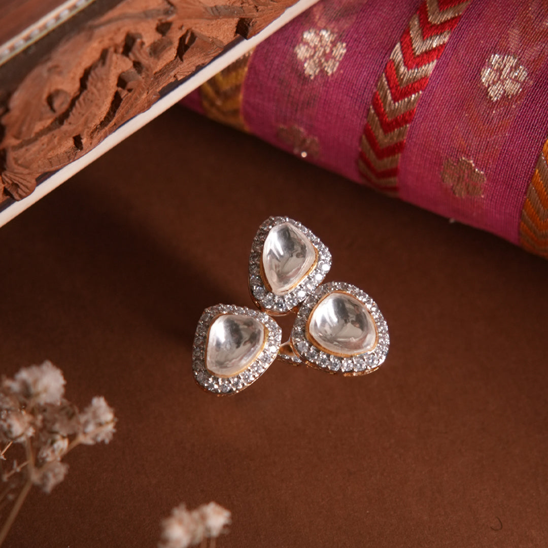 Artistic display of the Mira Ring by Vasundhara, with three gleaming kundan stones bordered by sparkling diamonds.