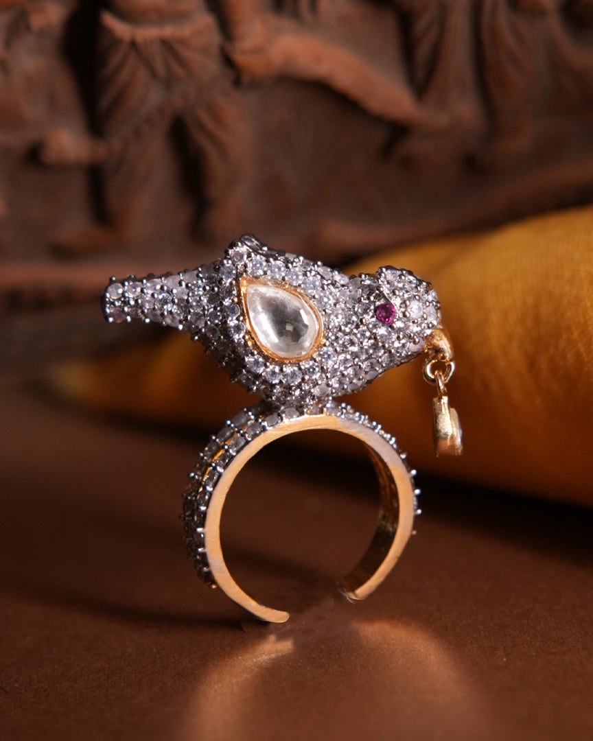 Sharanya Ring by Vasundhara, bird-shaped design with kundan and diamond accents, styled on a rich brown and gold backdrop.