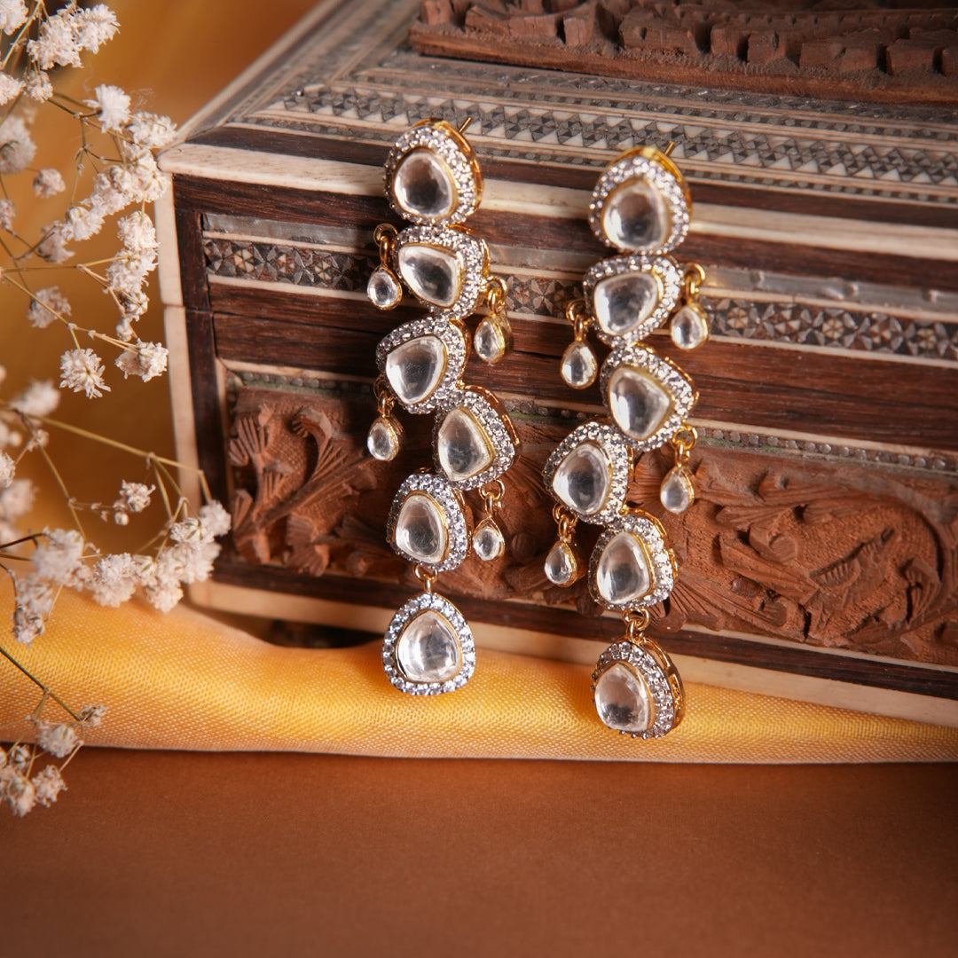 Vasundhara’s Prisha Earrings with layered kundan stones and sparkling crystals, set against an intricate wooden box.