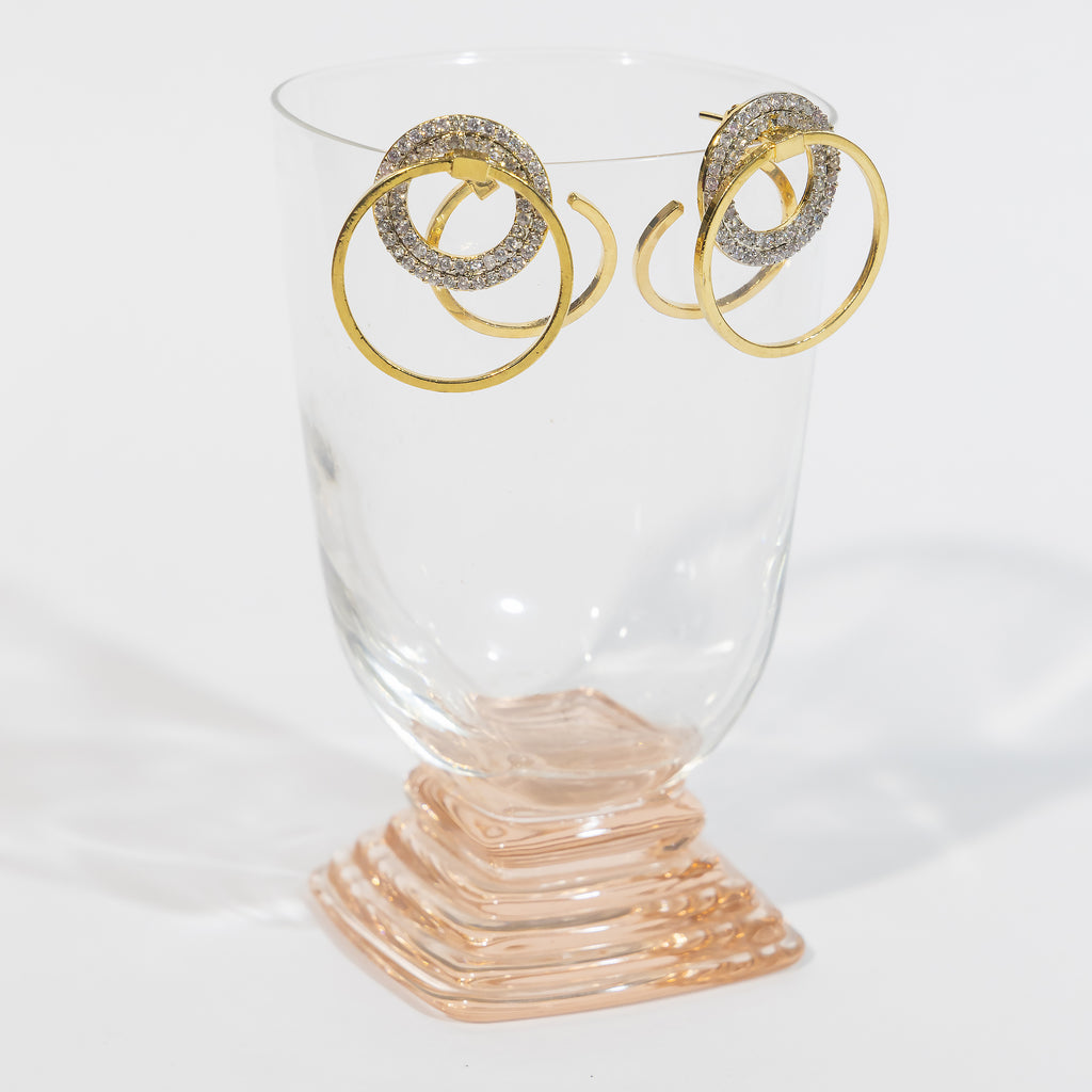 Affair Earrings with hoops is placed on a glass