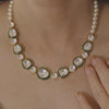 A close view of the Prisha Necklace, pairing lustrous pearls with green-edged kundan stones in a layered statement style.