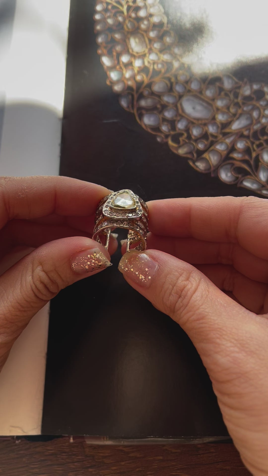 Vasundhara’s Iqra Ring, bold gold and diamond-studded band with a pear-shaped kundan stone placed on white display.